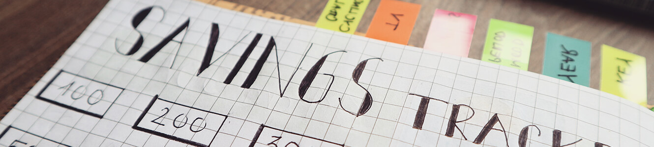 Image of graph paper with the wrods SAVINGS TRACKER hand written on it.