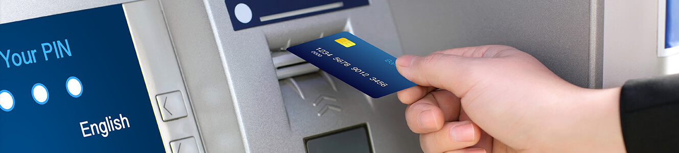 Photo of someone putting their ATM card into an ATM machine