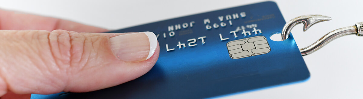 Hand holding a credit card that is being pulled away from them with a fish hook. Meant to represent the term 'phishing'.