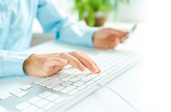 Person typing on a keyboard while looking at credit card. 