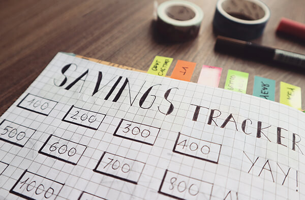 A hand drawn savings tracker on a piece of grided paper.