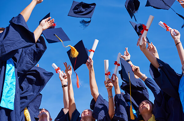 Crowd of college graduates tossing their graduation caps up in the air